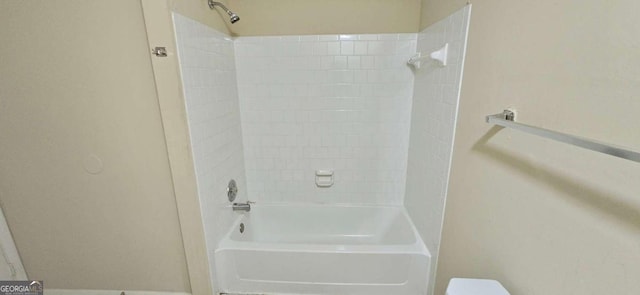 bathroom with tiled shower / bath combo and toilet