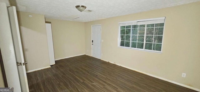 empty room featuring dark wood-type flooring and a textured ceiling