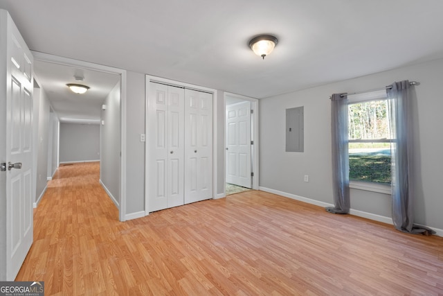 unfurnished bedroom with two closets, electric panel, and light hardwood / wood-style flooring