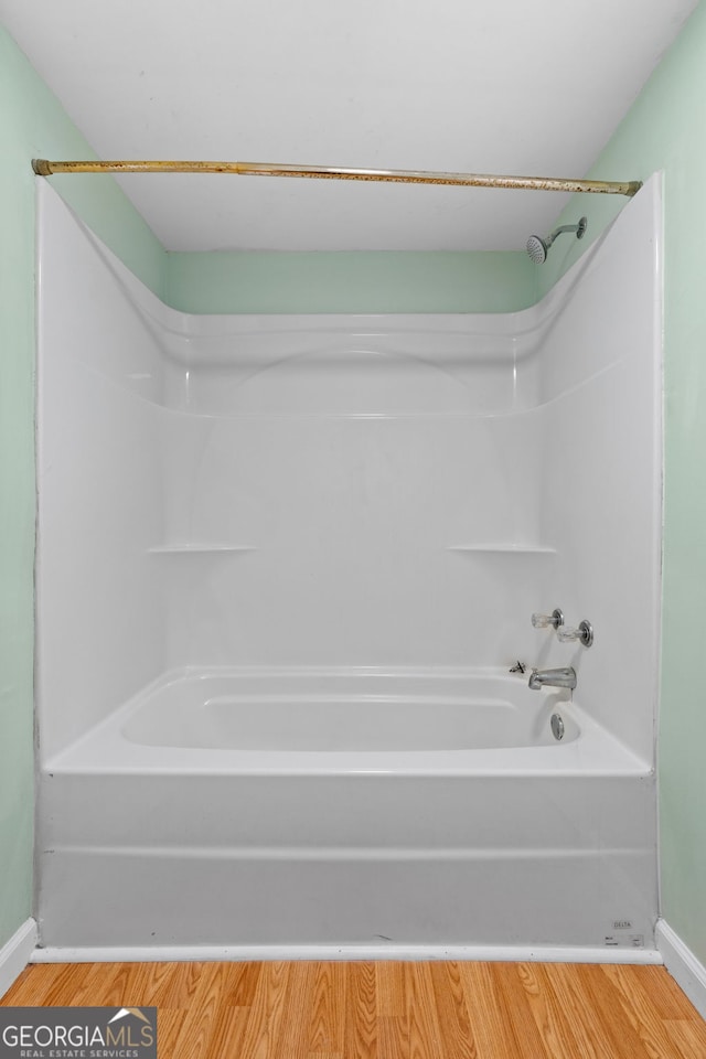 bathroom with wood-type flooring and bathing tub / shower combination