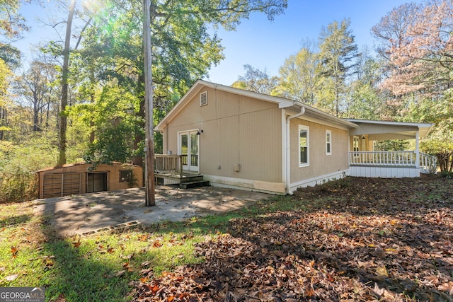 rear view of property with a storage unit and a porch