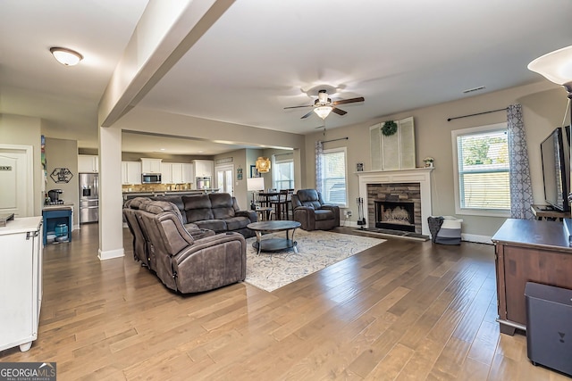 living room with ceiling fan, light hardwood / wood-style floors, and a fireplace