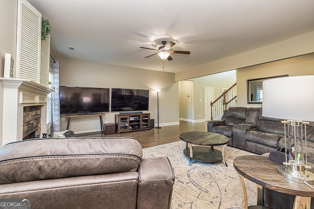 living room featuring hardwood / wood-style flooring, ceiling fan, and a fireplace