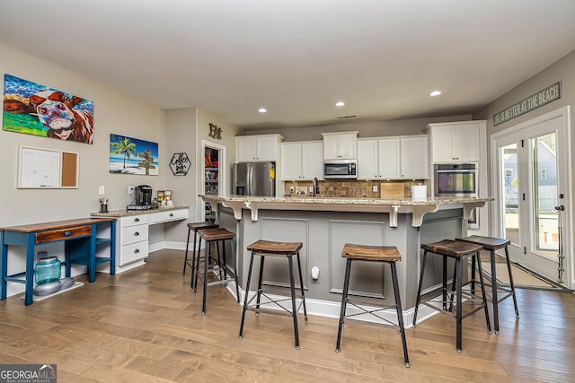 kitchen featuring a center island with sink, white cabinets, and appliances with stainless steel finishes