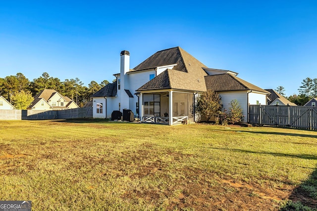 rear view of property featuring a sunroom and a lawn