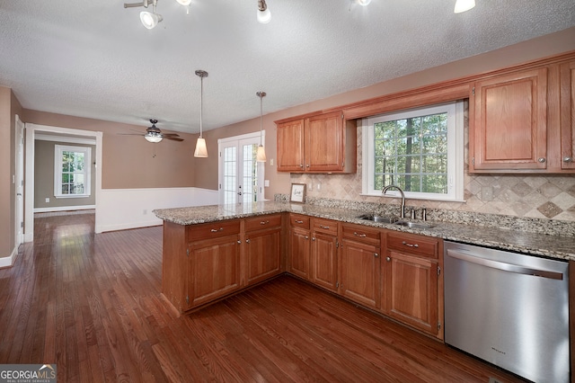 kitchen with kitchen peninsula, stainless steel dishwasher, a healthy amount of sunlight, dark wood-type flooring, and sink