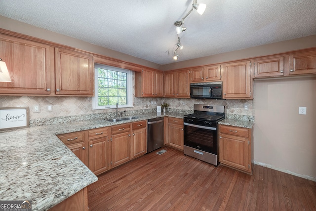 kitchen featuring dark hardwood / wood-style flooring, light stone countertops, sink, and appliances with stainless steel finishes