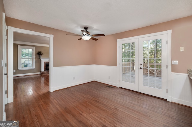 spare room featuring french doors, plenty of natural light, dark wood-type flooring, and a textured ceiling