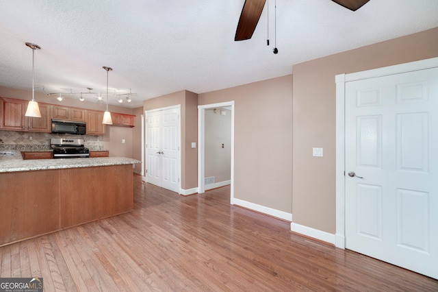 kitchen featuring backsplash, stainless steel stove, decorative light fixtures, light hardwood / wood-style floors, and kitchen peninsula