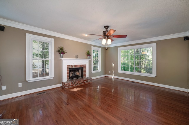 unfurnished living room featuring ceiling fan, a brick fireplace, dark hardwood / wood-style flooring, a textured ceiling, and ornamental molding