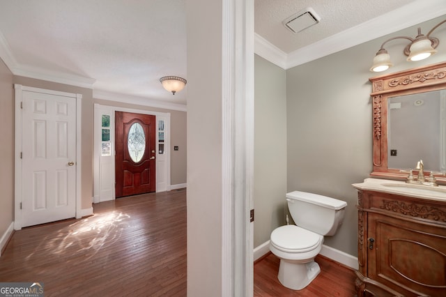 bathroom with ornamental molding, vanity, a textured ceiling, hardwood / wood-style floors, and toilet