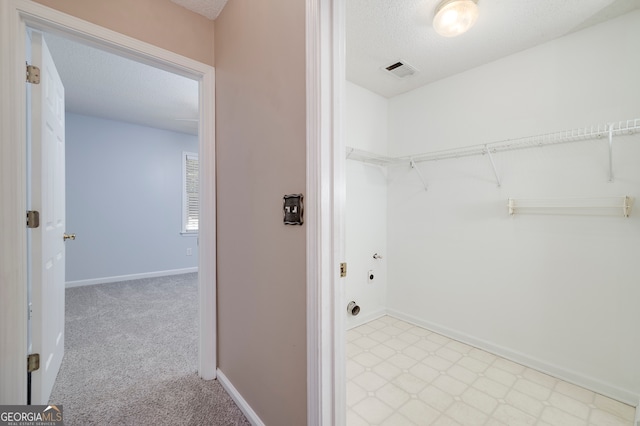 clothes washing area featuring light carpet and a textured ceiling