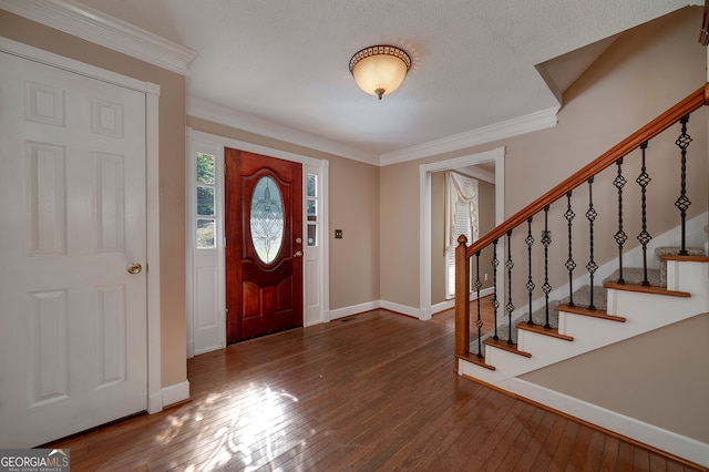 entrance foyer with a textured ceiling, wood-type flooring, and ornamental molding