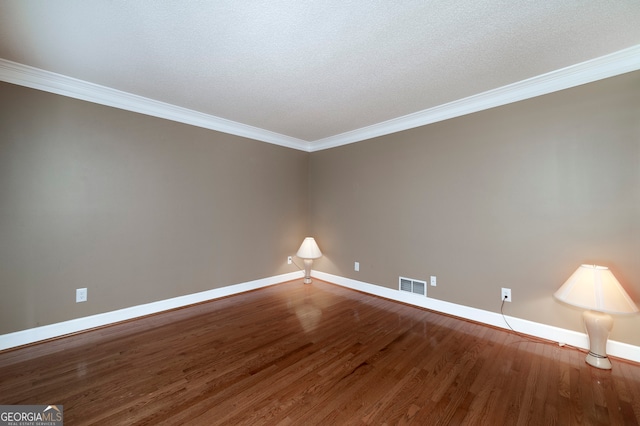 empty room with a textured ceiling, hardwood / wood-style flooring, and ornamental molding