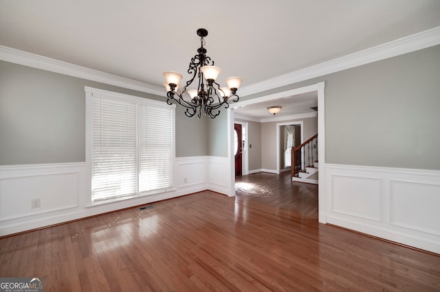 unfurnished dining area with dark hardwood / wood-style flooring, ornamental molding, and a notable chandelier