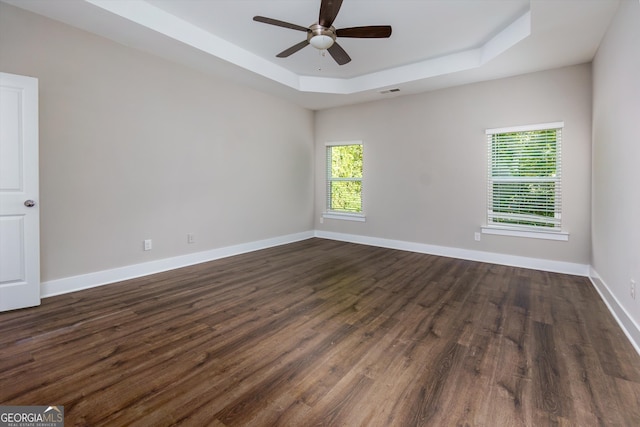 spare room featuring dark hardwood / wood-style flooring, a raised ceiling, and ceiling fan