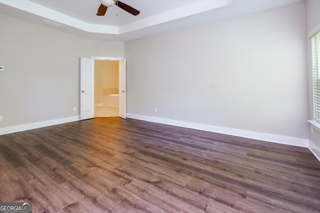 spare room featuring a tray ceiling, ceiling fan, and dark hardwood / wood-style flooring