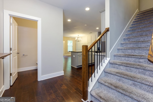 stairs with a notable chandelier and hardwood / wood-style flooring