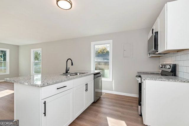 kitchen featuring a kitchen island with sink, white cabinets, sink, light wood-type flooring, and appliances with stainless steel finishes