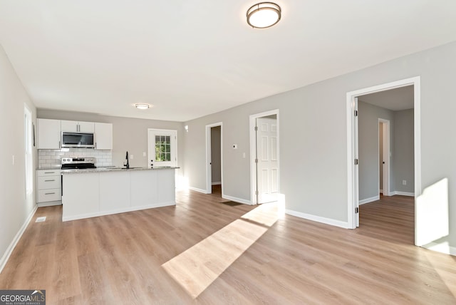 kitchen featuring sink, light hardwood / wood-style flooring, backsplash, white cabinets, and appliances with stainless steel finishes