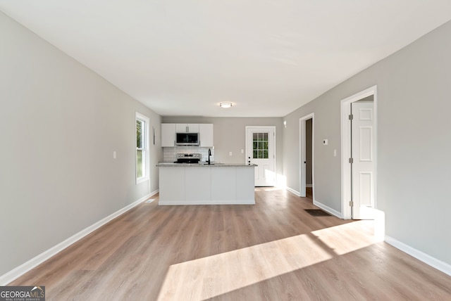 kitchen with white cabinetry, sink, tasteful backsplash, light hardwood / wood-style flooring, and appliances with stainless steel finishes