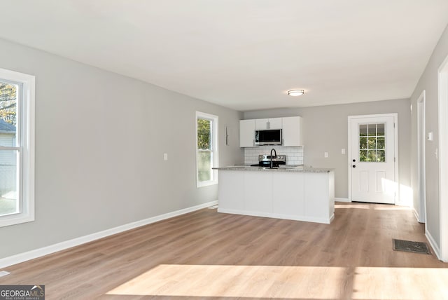 kitchen with plenty of natural light, light wood-type flooring, white cabinetry, and appliances with stainless steel finishes