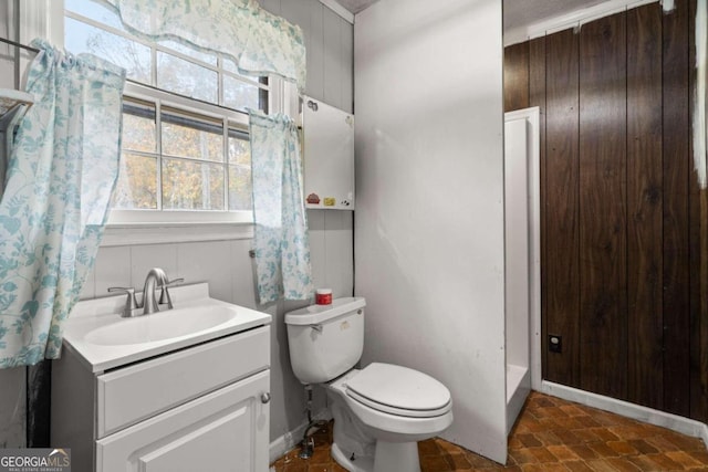 bathroom with vanity, toilet, and wooden walls