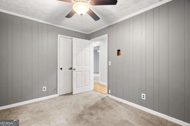 interior space featuring carpet floors, crown molding, ceiling fan, and wooden walls