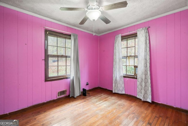 unfurnished room featuring ceiling fan, hardwood / wood-style floors, a textured ceiling, and ornamental molding