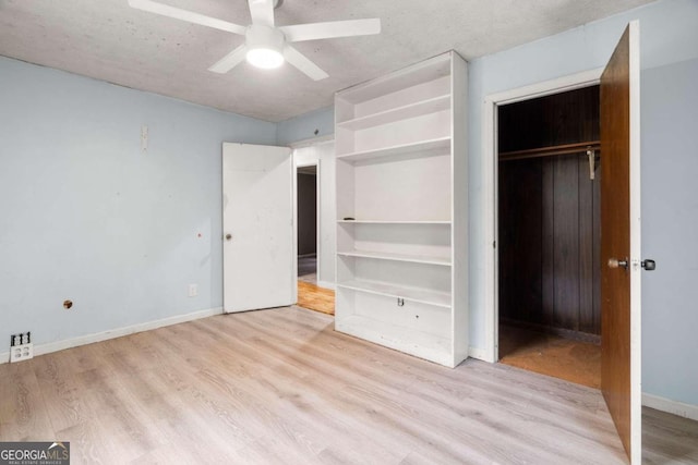 unfurnished bedroom with ceiling fan, light wood-type flooring, a textured ceiling, and a closet