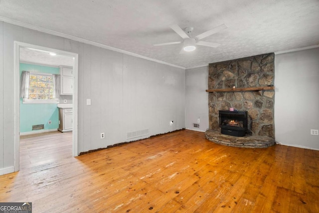 unfurnished living room with hardwood / wood-style floors, a textured ceiling, a wood stove, and ceiling fan