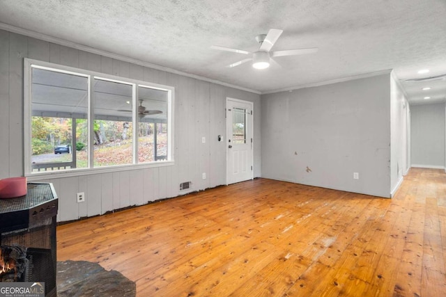 living room with a textured ceiling, light wood-type flooring, ceiling fan, and ornamental molding