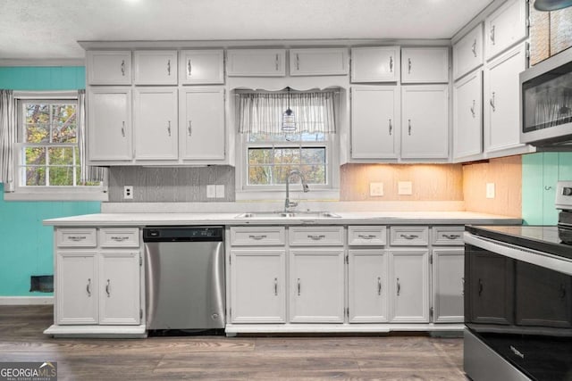 kitchen with white cabinetry, sink, dark wood-type flooring, stainless steel appliances, and decorative backsplash