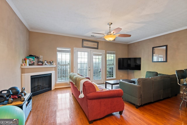 living room featuring wood-type flooring, a textured ceiling, ceiling fan, and crown molding