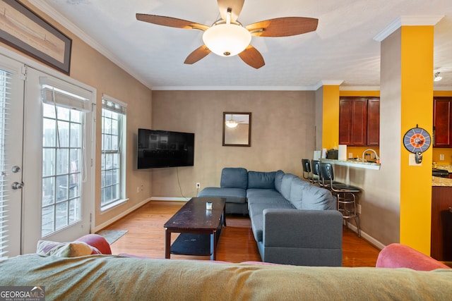 living room featuring light wood-type flooring, ceiling fan, and crown molding