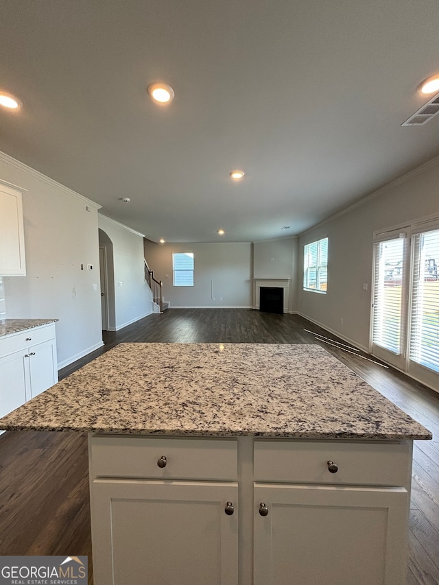 kitchen featuring white cabinetry, a kitchen island, light stone countertops, and dark hardwood / wood-style floors