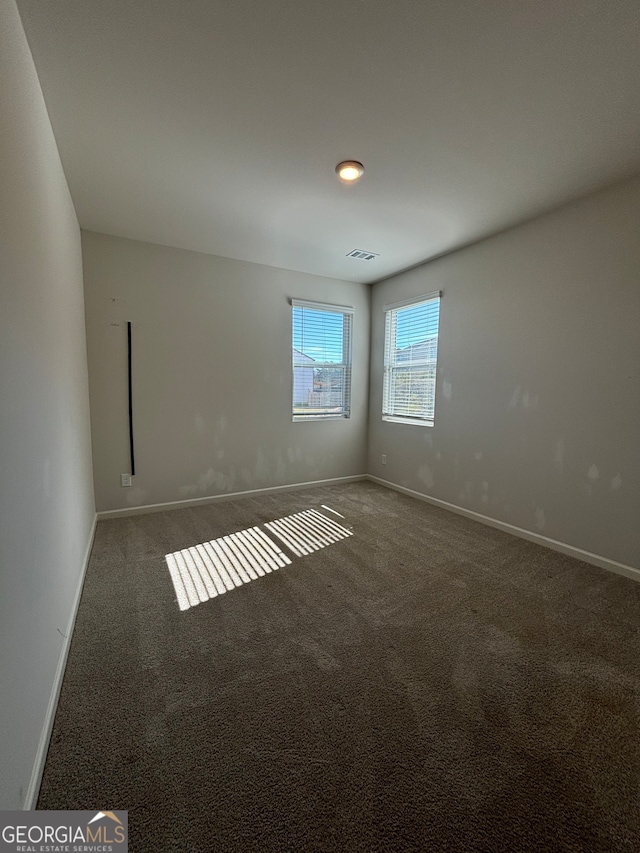 spare room with dark colored carpet