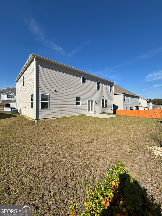 rear view of property featuring central AC unit, a patio area, and a lawn