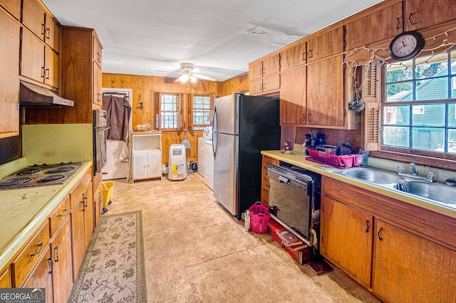 kitchen with stainless steel fridge, white gas cooktop, wooden walls, sink, and black dishwasher