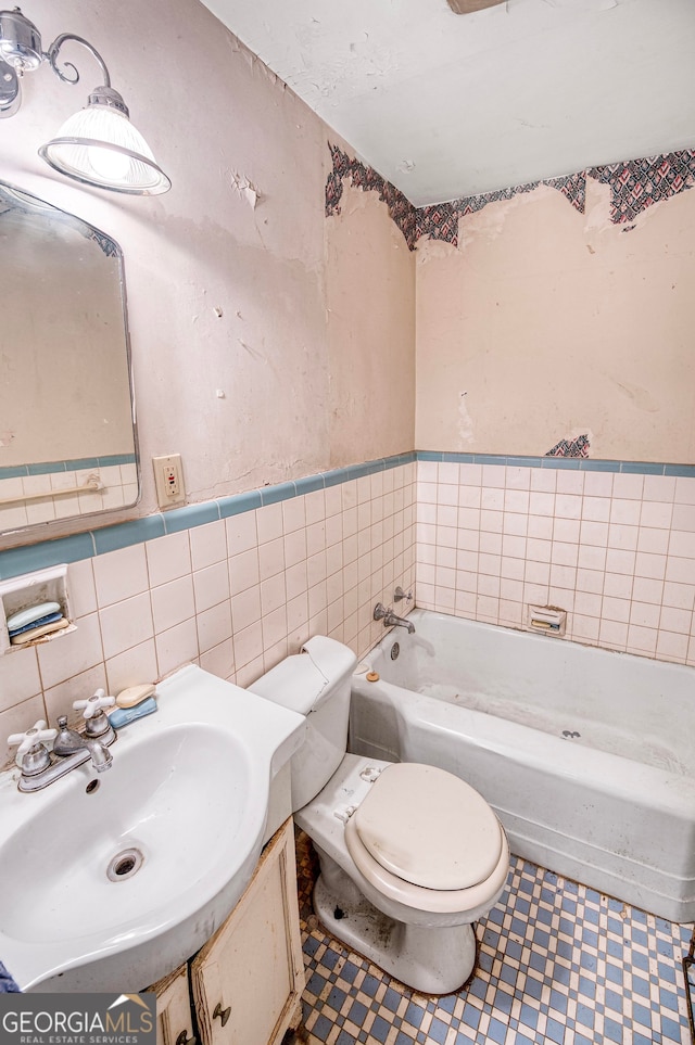 bathroom featuring a washtub, vanity, tile walls, and toilet