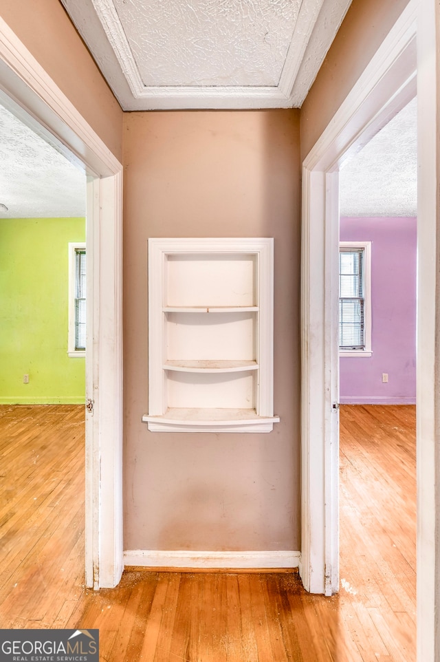 corridor featuring a textured ceiling, hardwood / wood-style flooring, and built in features