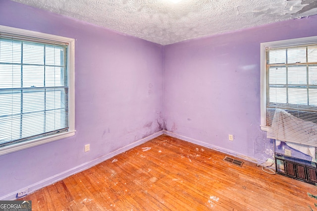 unfurnished room with wood-type flooring and a textured ceiling