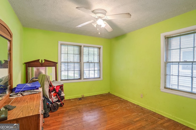 interior space featuring hardwood / wood-style floors, ceiling fan, and a textured ceiling