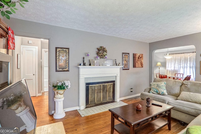 1778 Campbellton Rd SW, Atlanta, GA 30311 - living room with wood finished floors, a textured ceiling, baseboards, and a fireplace with flush hearth