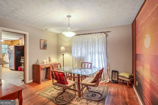 dining room featuring hardwood / wood-style floors, a textured ceiling, and wooden walls