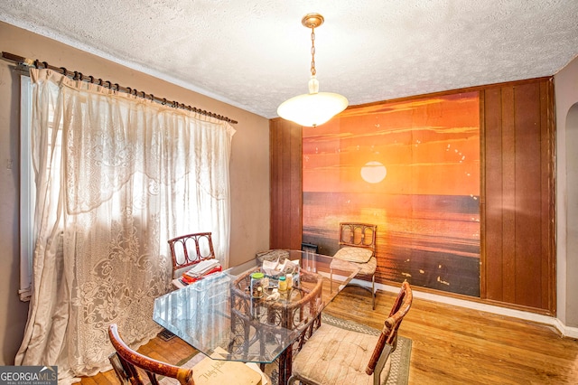 dining area featuring hardwood / wood-style floors, a textured ceiling, and wood walls