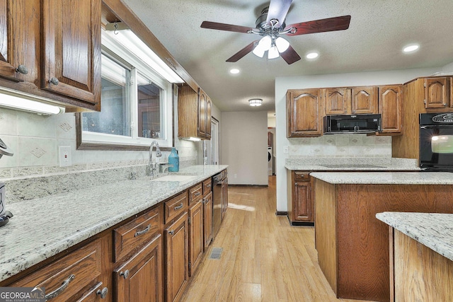 kitchen featuring black appliances, sink, a textured ceiling, and light hardwood / wood-style flooring