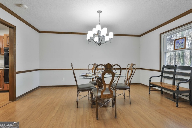 dining room featuring a textured ceiling, crown molding, a notable chandelier, and light wood-type flooring