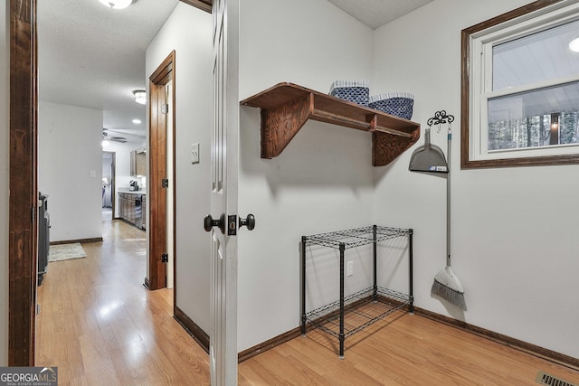 corridor with a textured ceiling and light wood-type flooring