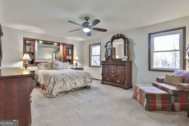 bedroom featuring a textured ceiling, light colored carpet, and ceiling fan